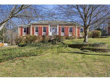 Charming brick home with red shutters and a well-manicured front yard featuring mature landscaping at 663 Foxcroft Circle Se, Marietta, GA 30067