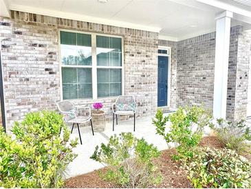 Inviting front porch featuring brick facade and seating area with two chairs and side table at 325 Caledonia Ct, Peachtree City, GA 30269