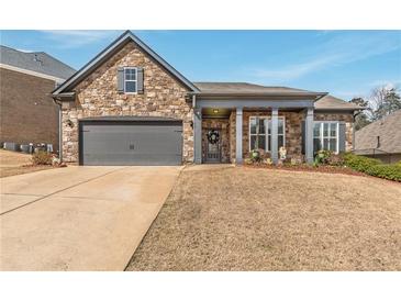 Charming stone home featuring a two-car garage, covered porch with stone columns and a well-manicured lawn at 407 After Glow Smt, Canton, GA 30114