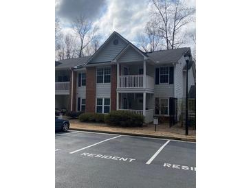 Two-story condo with balcony, brick facade, and designated resident parking at 124 Streamside Dr # 24, Roswell, GA 30076