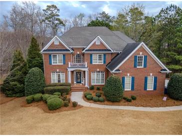 Traditional brick home with manicured landscaping, blue shutters, and a balcony above the arched entry at 1320 Kildare Ct, Snellville, GA 30078