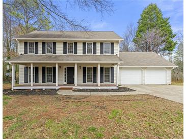 Charming two-story home with a welcoming front porch and a two-car attached garage and well-manicured landscaping at 5215 Willow Creek Overlook, Woodstock, GA 30188