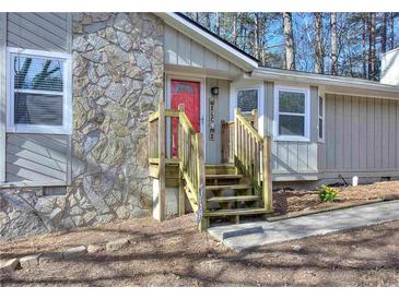 Charming home featuring stone accents, a welcoming staircase, and a bright red front door at 2493 Cherie Glen Trl, Snellville, GA 30039