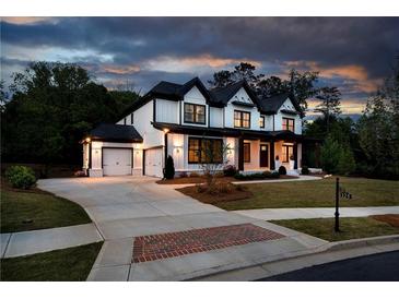 Beautiful two-story home with a three-car garage, a well-manicured lawn, and a brick-laden driveway at 320 Dodd Ln, Alpharetta, GA 30005