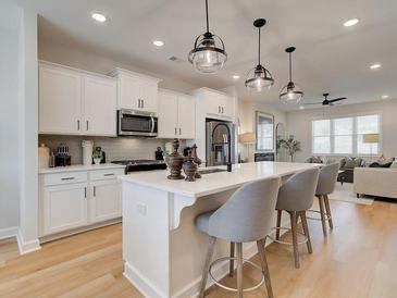 Bright kitchen with stainless appliances, white cabinetry, quartz counters, and stylish pendant lighting over a large island at 4814 Floydwood Ln, Mableton, GA 30126