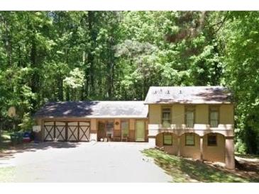 Two-story home featuring a spacious multi-car garage, surrounded by lush greenery and mature trees at 5531 Four Winds Sw Dr, Lilburn, GA 30047