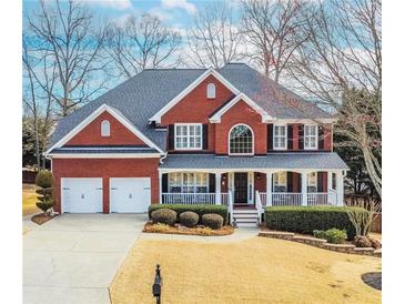 Charming two-story brick home featuring a welcoming front porch, manicured lawn, and a two-car garage at 2059 Sugar Springs Dr, Lawrenceville, GA 30043