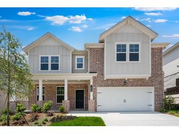 Charming two-story home featuring a brick facade, white trim, a covered porch, and a two-car garage at 1356 Auburn Glen Rd, Dacula, GA 30019