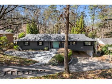 Ranch-style house with charcoal exterior, light blue front door, and driveway leading to a carport at 3240 Pinestream Nw Rd, Atlanta, GA 30327