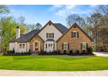 Charming two-story home featuring stone and brick accents, complemented by a well-manicured lawn and mature trees at 2410 Glade Overlook, Cumming, GA 30041