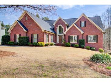 Beautiful brick home with well-manicured lawn and mature trees on a sunny day at 1300 Village Oaks Ln, Lawrenceville, GA 30043