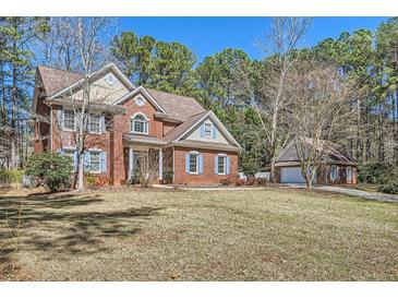 Charming two-story brick home with blue shutters and attached garage and shed in a wooded area at 100 Hamilton Glen Ct, Fayetteville, GA 30215