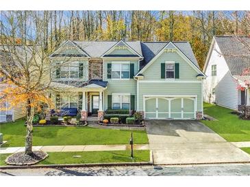 Charming two-story home with green siding, shutters, manicured lawn and attached two car garage at 4273 Creekrun Cir, Buford, GA 30519