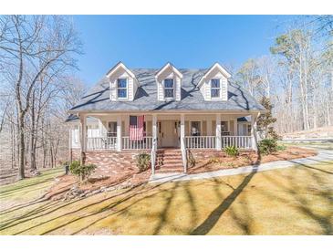 Charming two-story home featuring a welcoming porch and landscaped front yard and American flag at 170 River Cove Rdg, Social Circle, GA 30025
