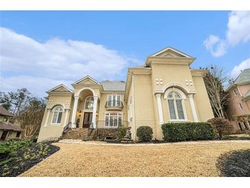 Elegant two-story home with a manicured front yard and stunning architectural details under a partly cloudy sky at 4040 Annecy Dr, Atlanta, GA 30331