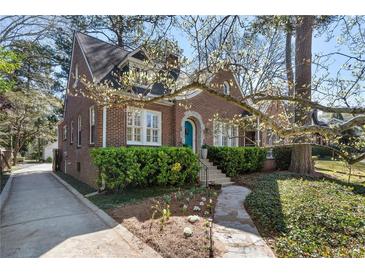 Charming brick home featuring a blue door, lush landscaping, and a stone walkway to the front entrance at 595 Ridgecrest Ne Rd, Atlanta, GA 30307