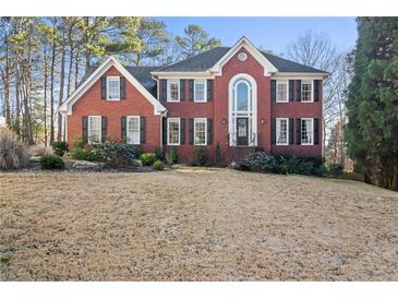 Beautiful brick home with black shutters, arched entryway, and well-manicured landscaping at 1701 Crowes Lake Ct, Lawrenceville, GA 30043