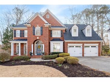 Charming brick two-story home boasts a three-car garage and meticulously landscaped front yard at 1026 Wellesley Crest Dr, Woodstock, GA 30189