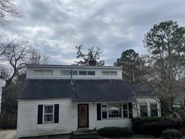 Quaint one-story home with a unique architectural design and dark shutters on a cloudy day at 1867 Dresden Dr, Atlanta, GA 30319