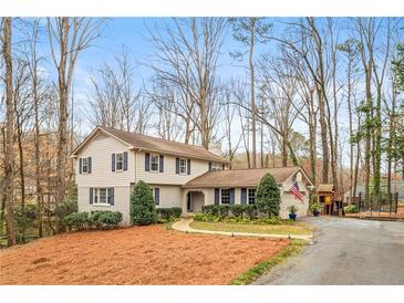 Charming two-story home featuring blue shutters, well-manicured landscaping, and a spacious front yard at 345 W Spalding Dr, Sandy Springs, GA 30328