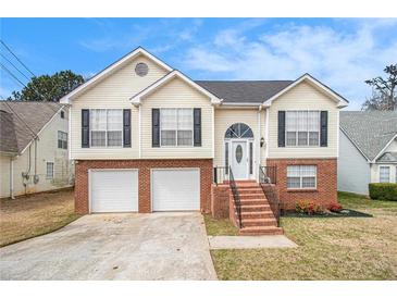 Charming split-level home featuring a brick facade, attached two-car garage, and a welcoming front entrance with stairs at 1947 Phillips Lake Blf, Lithonia, GA 30058