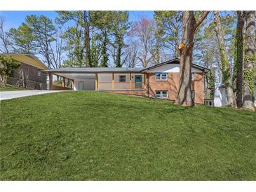 Charming brick home with a vibrant blue front door and a lush, green lawn at 5277 Cardinal Nw Ln, Lilburn, GA 30047