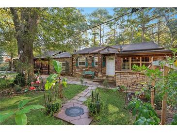 Charming stone cottage with lush front yard, stone walkway, and mature trees, offering a peaceful setting at 80 Rountree Rd, Riverdale, GA 30274