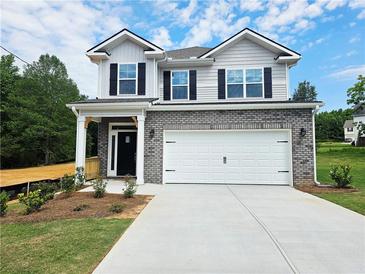 Two-story home featuring a brick and vinyl facade, a two-car garage, and a well-manicured front lawn at 145 Scarlett Place Dr, Bowdon, GA 30108