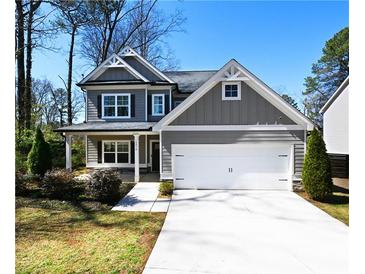 Charming two-story home featuring a covered front porch, gray siding, and a two-car garage at 2076 Greenridge Se Rd, Smyrna, GA 30080