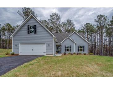 Charming single-Gathering home features a two-car garage, light gray siding, manicured lawn, and black shutters at 83 Malcom Rd, Covington, GA 30014