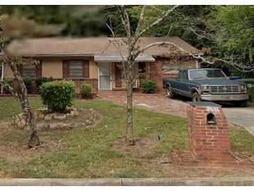 Cozy brick home featuring a well-maintained lawn and mature trees, offering a charming curb appeal at 2541 Santa Barbara Nw Dr, Atlanta, GA 30318