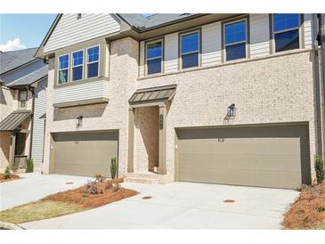 Charming townhome exterior with light brick, tan trim, two-car garage, and well-manicured landscaping at 3900 Allegretto Cir # 51, Atlanta, GA 30339