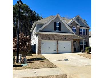 Charming two-story home with a two-car garage and gray and brick exterior on a sunny day at 3831 Village Crossing Ln, Ellenwood, GA 30294