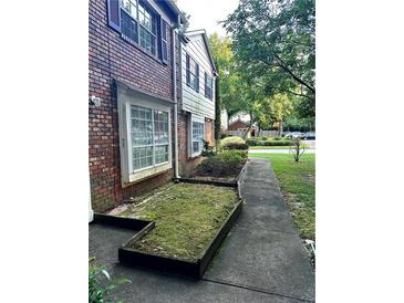 Exterior view of a brick home with a small side yard covered in moss and a sidewalk leading to the entrance at 2574 Stratford Ln, Morrow, GA 30260