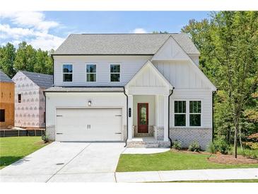 Charming two-story home boasts a welcoming front porch and attached two-car garage at 104 Cedar Brook Dr, Holly Springs, GA 30115