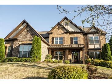 Handsome two-story brick home with stone accents, manicured lawn, and inviting covered front porch at 4025 Toulon Ln, Cumming, GA 30040