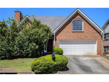 Brick home featuring an attached garage, manicured landscaping and architectural detailing at 4484 Hunters Way, Stone Mountain, GA 30083