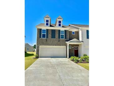 Beautiful two-story townhome with a three car garage, landscaped yard, and neutral brick facade at 2560 Quarterdeck Dr, Cumming, GA 30041