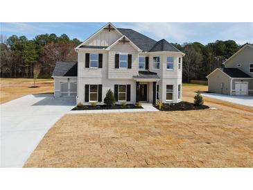 Two-story home boasts a light-colored facade, dark shutters, and a manicured front yard at 3154 Rosebud Rd, Loganville, GA 30052