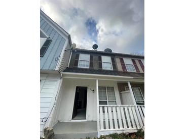 Two-story townhome with neutral colors, well-kept facade and open front porch at 498 Prince Of Wales, Stone Mountain, GA 30083