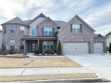 Stately gray brick home with manicured landscaping, three car garage and inviting curb appeal at 3988 Two Bridge Drive, Buford, GA 30519
