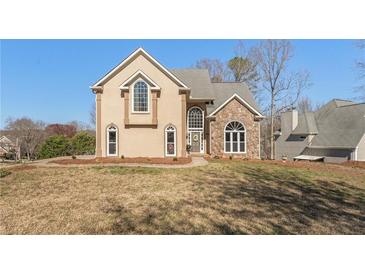 Two-story home with a blend of stucco and stone, arched windows, and a well-manicured lawn at 607 Delphinium Nw Blvd, Acworth, GA 30102