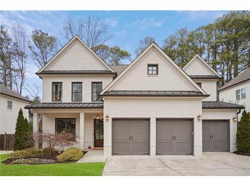 Beautiful two-story painted brick home with a three-car garage and a well-manicured lawn at 1884 Canmont Ne Dr, Brookhaven, GA 30319