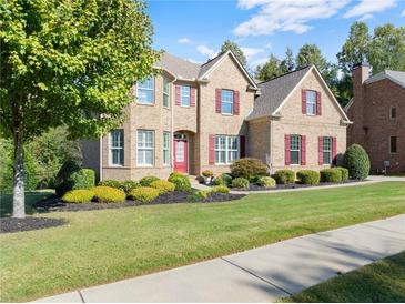 Charming two-story brick home with manicured lawn, mature tree, and red accents against a beautiful blue sky at 4070 Preserve Crossing Ln, Cumming, GA 30040