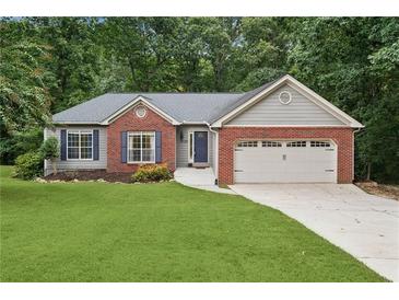 Charming single-Gathering home with brick accents, two-car garage, and a well-manicured lawn and mature trees at 4125 Gables Pl, Buford, GA 30519