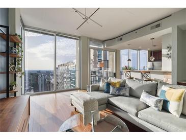 Bright living room featuring a gray sectional sofa and floor-to-ceiling windows with expansive city views at 855 Peachtree Ne St # 2801, Atlanta, GA 30308