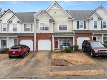 Charming townhome with a brick facade and attached garage, showcasing inviting curb appeal in a residential setting at 2427 Millbank Ct, Lawrenceville, GA 30043