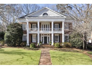 Elegant two-story brick home featuring a columned front porch and manicured lawn at 1386 Wesley Nw Cir, Atlanta, GA 30327