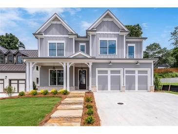 Beautiful two-story home with gray siding, white trim, a front porch, three-car garage and manicured front yard at 7285 Cordery Rd, Cumming, GA 30040