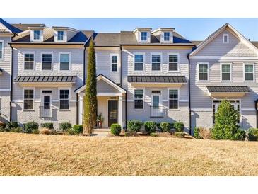 Charming three-story townhome with a manicured front yard and classic architectural details at 10035 River Rock Dr, Roswell, GA 30076